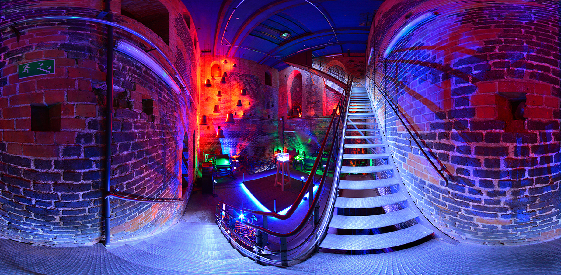 Zdjęcie panoramiczne zrobione ze schodów. W dole widok na salę na poziomie drugim, po prawej dalsze schody prowadzące na szczyt wieży.