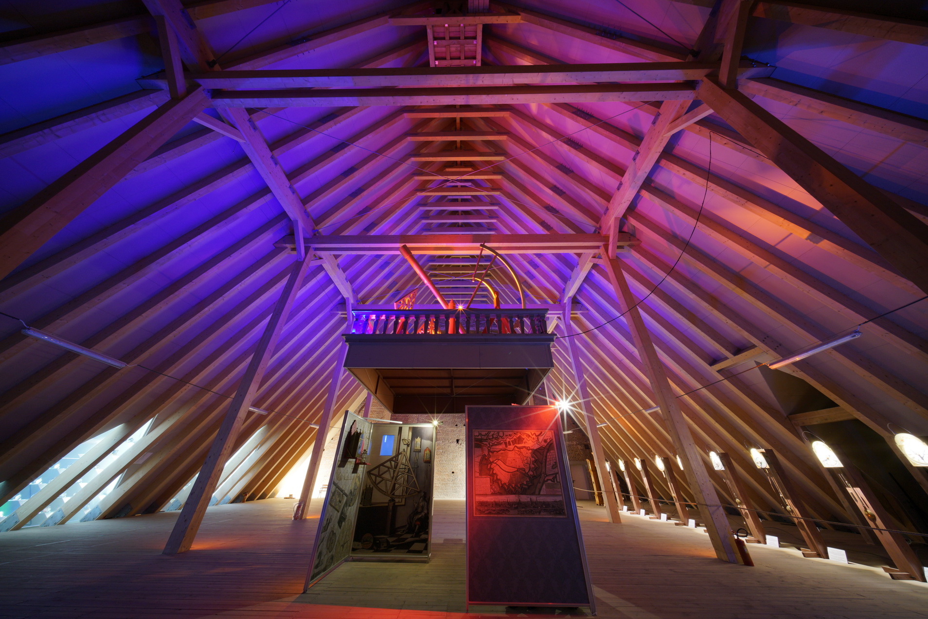 Wystawa na poddaszu. Makieta obserwatorium Jana Heweliusza. Widok z dołu, na drewniany strop, podświetlony na różowo i fioletowo.