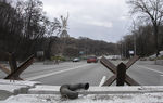 Zdjęcie. Pomnik z mieczem na wzgórzu. Ulica w dolinie. Ustawione zasieki i samochody