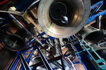 Zdjęcie. Dzwony carillonu, widok od dołu. Widać wnętrze dzwonów i ich serca. Zawieszone na metalowej konstrukcji. W tle ceglane ściany.