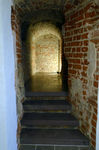 Zdjęcie, wnętrze galerii. Wąskie przejście o starych, ceglanych ścianach i sklepieniu. Do wejścia prowadzą trzy kamienne schody. U końca tunelu oświetlona, ceglana ściana.