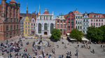 alt="Panorama Długiego Targu w Gdańsku z Dworem Artusa, Fontanną Neptuna i kolorowymi kamienicami, widziana z góry w słoneczny dzień."