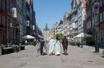 Zdjęcie. Dwaj mężczyźni i dwie kobiety idą ulicą Długą w kierunku Złotej Bramy. Ubrani w stroje jak z 18 wieku.
