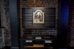 Zdjęcie ekspozycji w Muzeum Bursztynu. Na ciemnej planszy w tle w centralnym miejscu portret średniowiecznej damy trzymającej różaniec z kulą (pomander), z której wydobywały się zapachy i dym. Pozostała częśc tablicy to tekst informacyjny. Pon