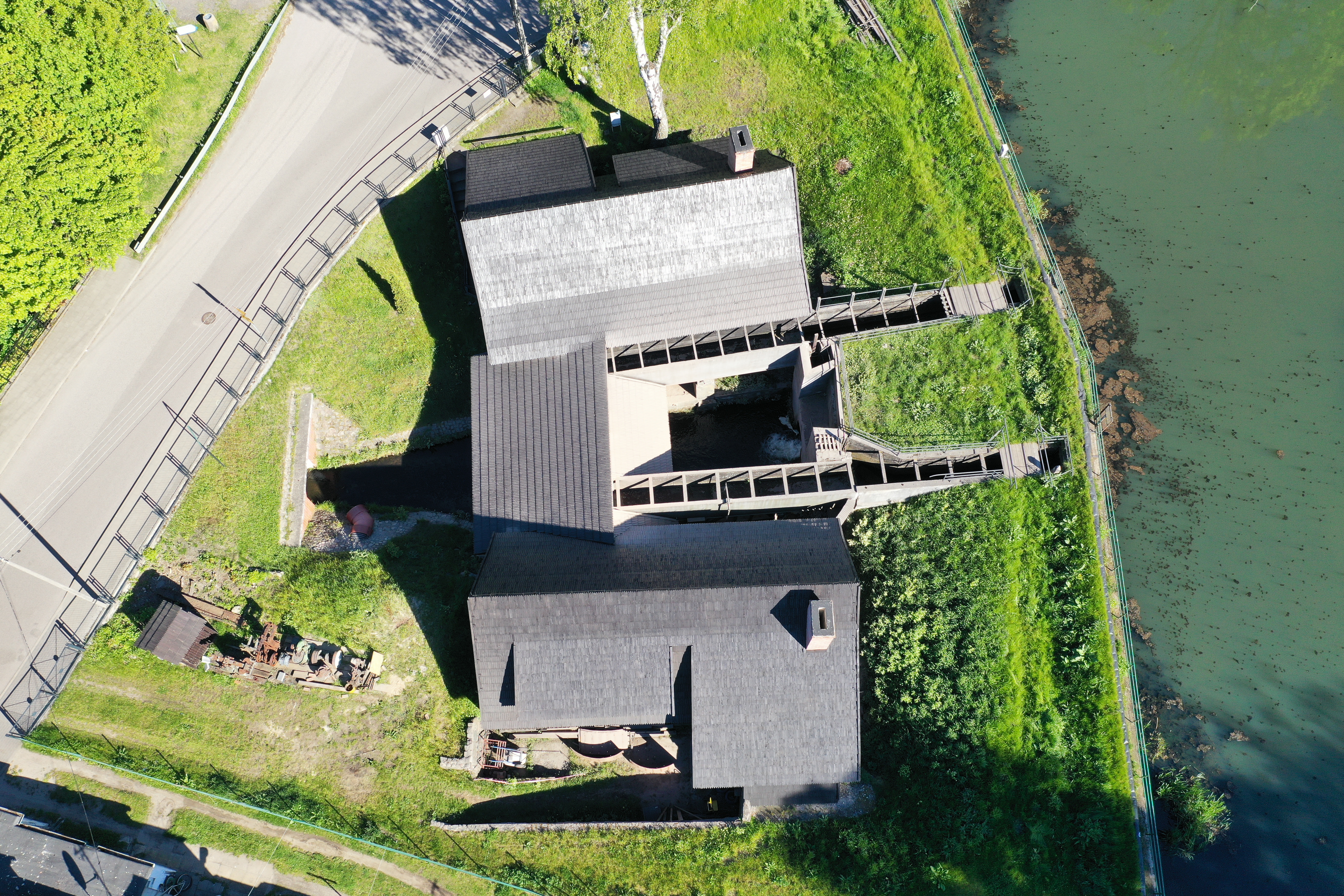 Hammerforge seen from bird's eye view. Wooden building, surrounded by grass field and river.