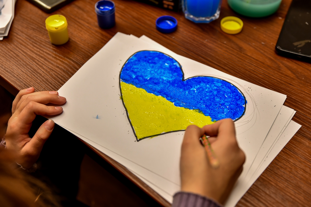 Rysunek malowany farbkami przez dziecko. To serce, w barwach narodowych Ukrainy, niebieskim i żółtym.