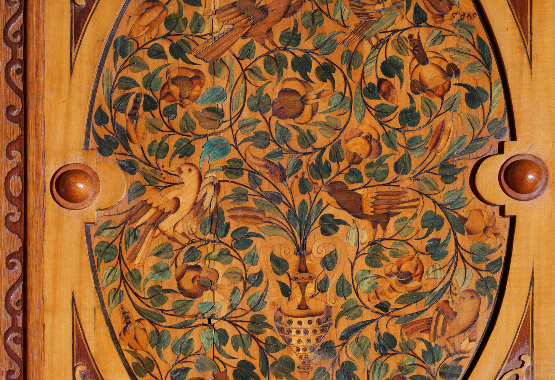 Fragment boazerii, zbliżenie na intarsje. Ornamenty z kwiatów i liści, między nimi dwa ptaki.