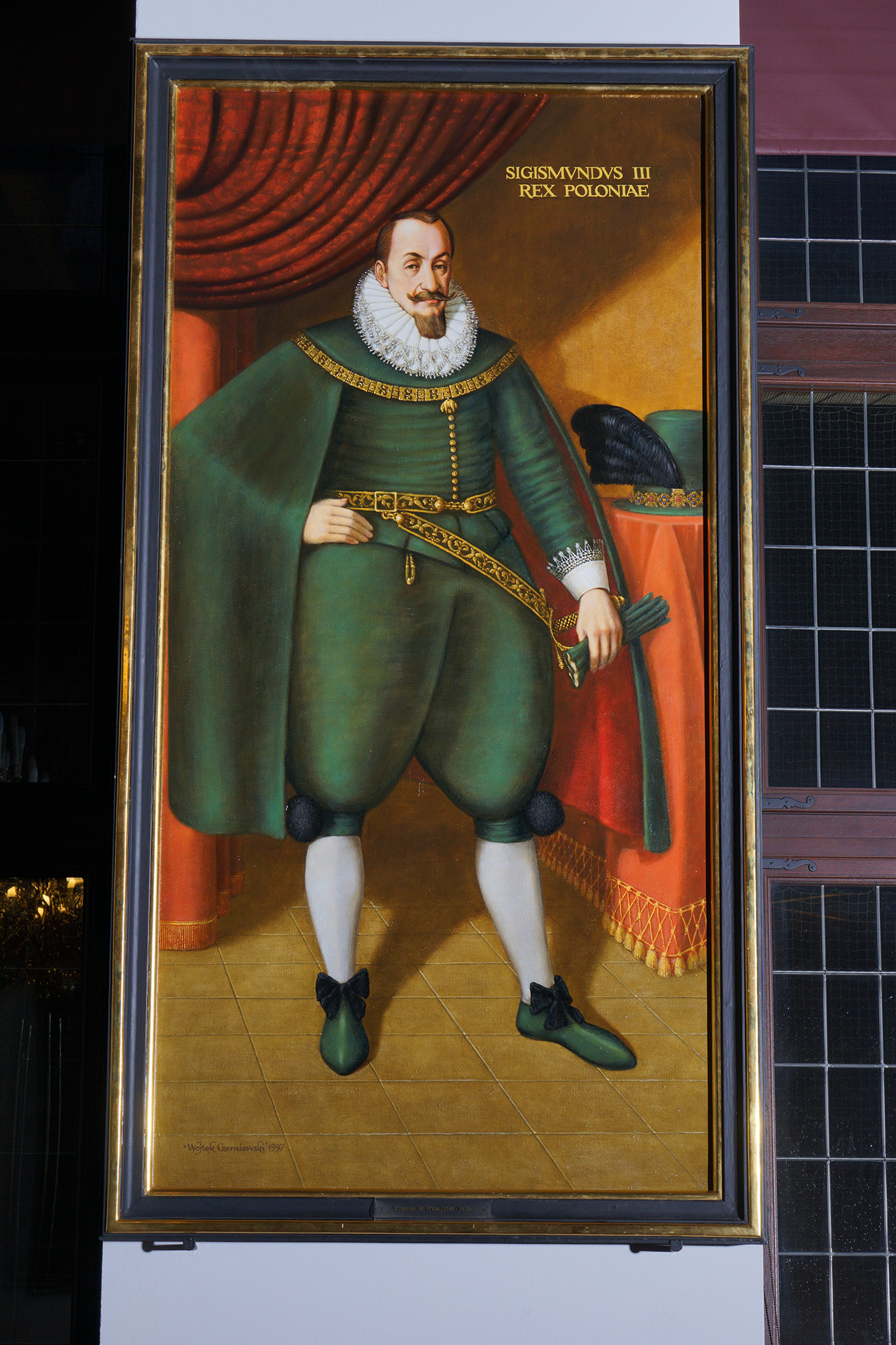 Portret króla Zygmunta III w Wielkiej Sali Wety. Ubrany w zielony strój, na ramionach ma pelerynę a pod szyją kryzę.