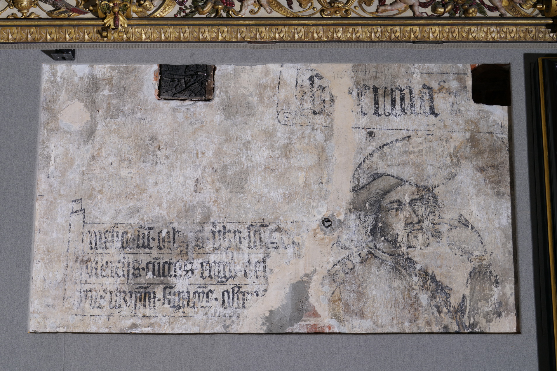 Fragment dekoracji malarskiej na ścianie Sali Czerwonej. Portret mężczyzny, po lewej tekst, niewyraźny.