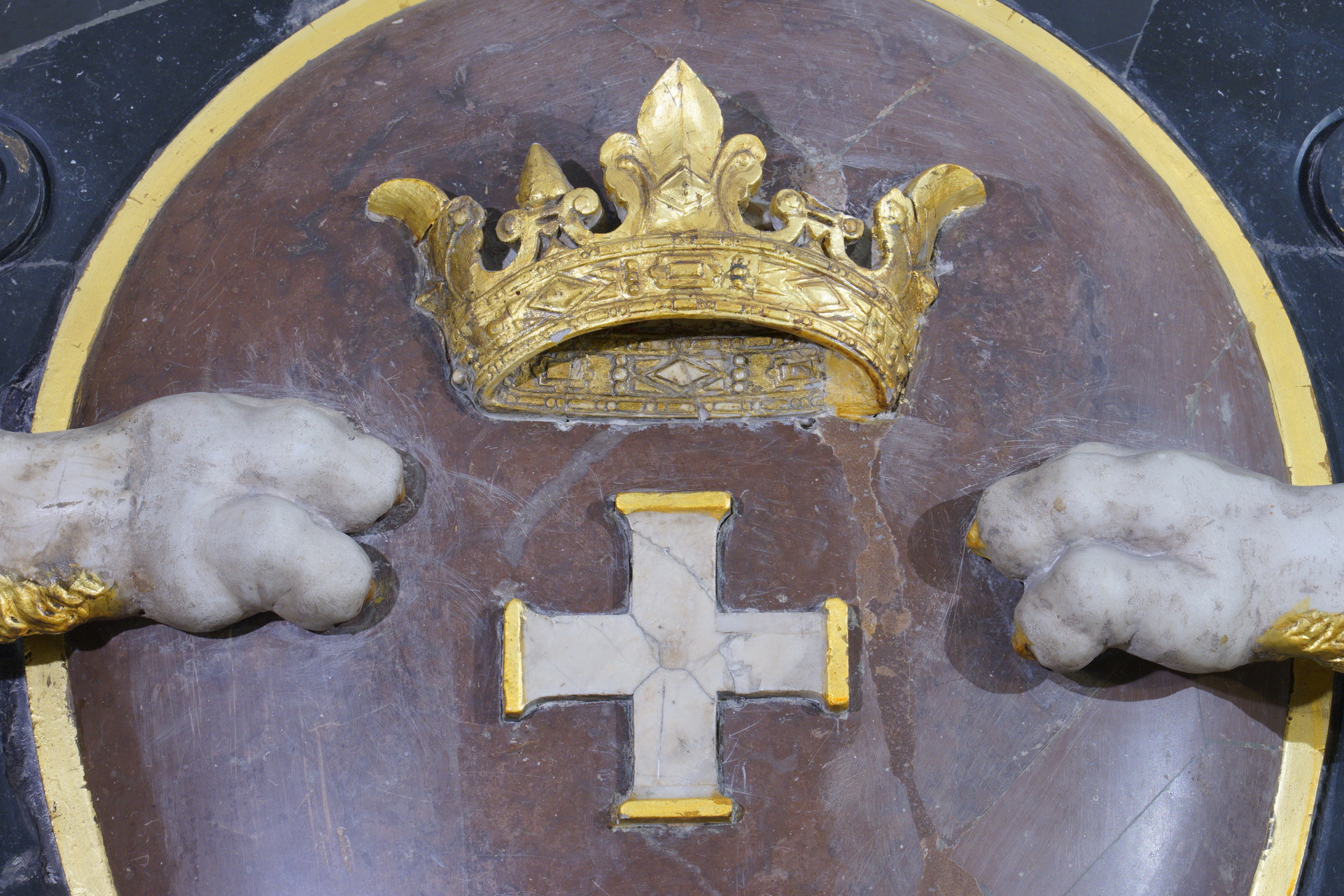 Fragment herbu Gdańska, duże zbliżenie. Złota korona, pod nią jeden z krzyży. Po obu stronach na godle lwie łapy.